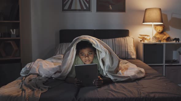 Boy Using Tablet in Bed