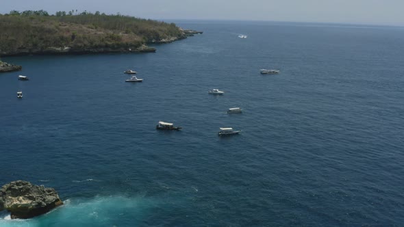 snorkeling tour boats anchored in the blue ocean around crystal bay in nusa penida bali on a sunny d
