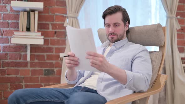 Casual Young Man Reading Documents on Sofa