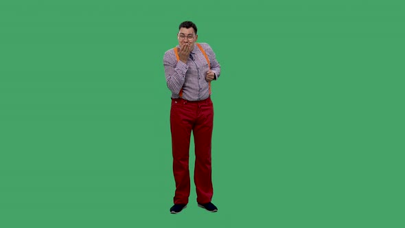 Portrait of a Man in Glasses in a Plaid Shirt with Orange Suspenders in the Studio on a Green Screen