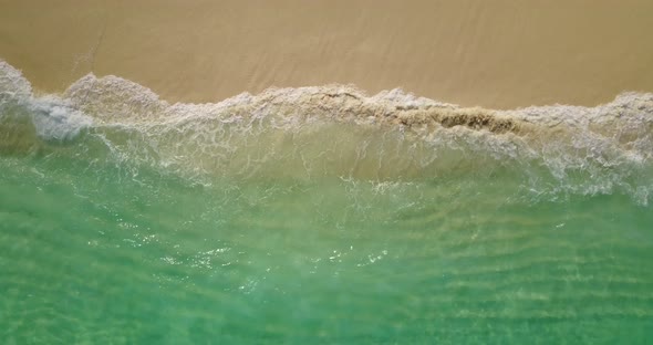 Daytime flying abstract view of a white paradise beach and aqua blue ocean background in vibrant 4K