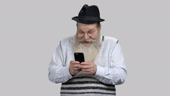 Old Aged Man Having Fun Online with His Smartphone