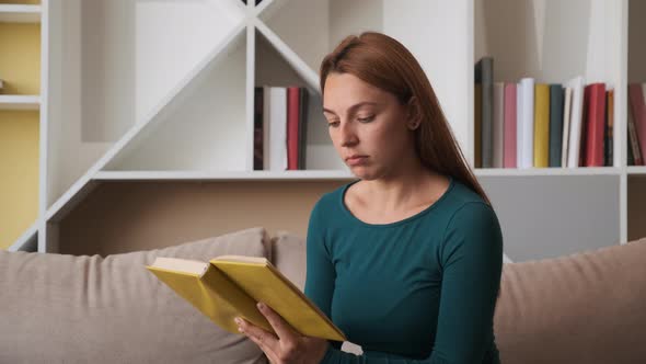 Young Woman Sit on Sofa at Home. Reading a Book