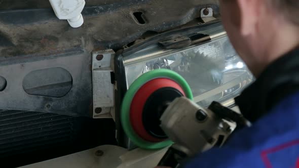Closeup of a Mechanic Polishes the Headlight with a Grinding Machine