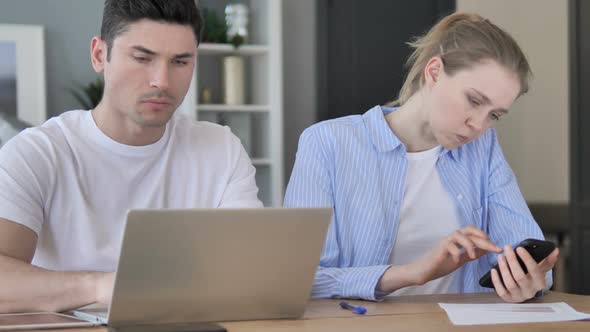 Pensive Designers Working Online on Laptop and Smartphone