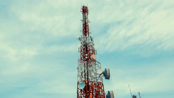 Time lapse of telecommunication tower against sky and clouds in background