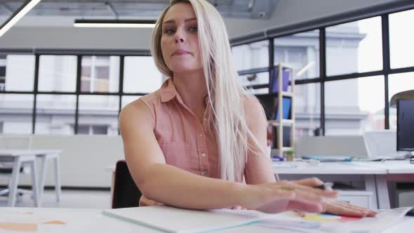 Caucasian businesswoman having video chat going through paperwork in modern office