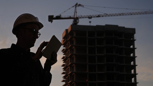 Construction manager using tablet on building site.