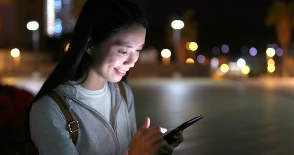Woman checking on cellphone at night