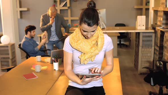 Female business executive using digital tablet while her coworker interacting in background