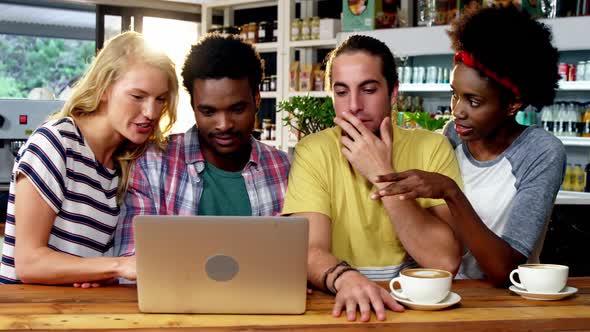 Group of friends using laptop while having cup of coffee