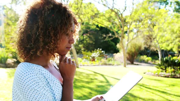 Woman using digital tablet in park