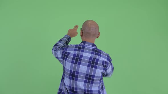 Rear View of Bald Hipster Man Touching Something