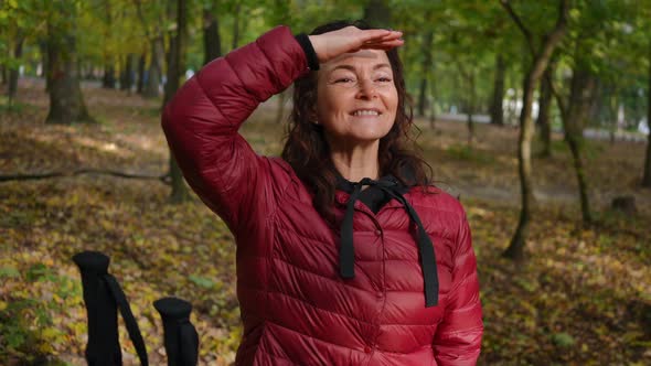 Portrait of Charming Mature Smiling Woman Looking Away Holding Hand at Forehead Taking Ski Poles