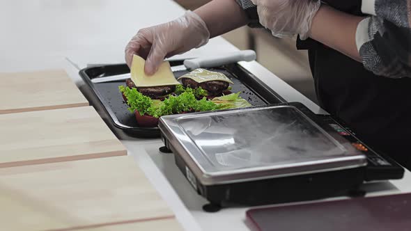 Cook Puts Plate of Melted Cheese on Beef Patty