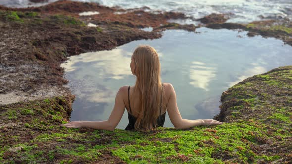 Young Woman Tourist Relax in a Natural Little Pond with Seawater at the Pantai Tegal Wangi Beach on