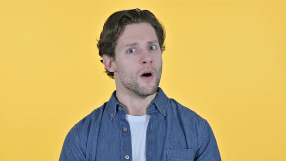 Stunned Young Man Feeling Shocked on Yellow Background