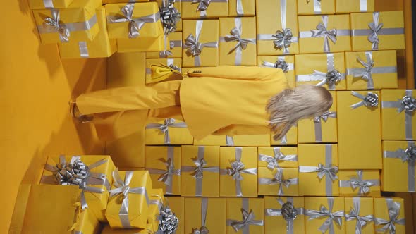 An Attractive Blonde in a Yellow Suit and a Yellow Purse in Her Hands Poses Against the Background