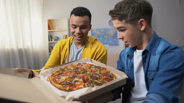 Two Multiracial Friends Opening Box With Pizza for Student Party, Food Delivery