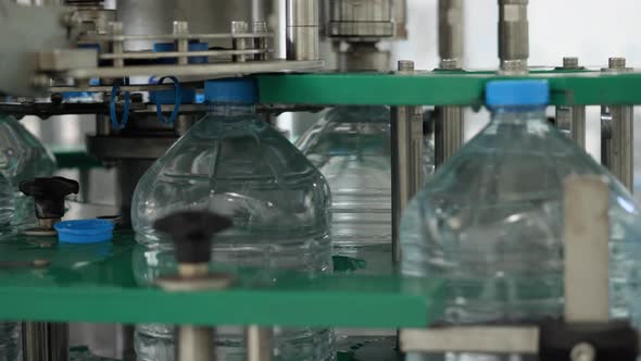 Five-liter bottles on the capping machine. Drinking Water Production Line at Food Processing Plant