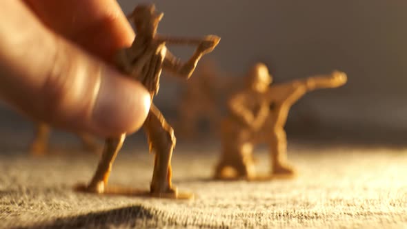 A Human Hand Moves a Toy Soldier Forward on an Imaginary Battlefield