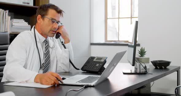 Physician talking on landline at desk 