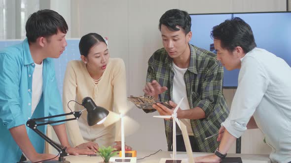 Asian Engineers Group Discussing About Green Circuit Board While Testing The Wind Turbine