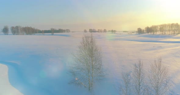 Aerial View of Cold Arctic Field Landscape Trees with Frost Snow Ice River and Sun Rays Over Horizon