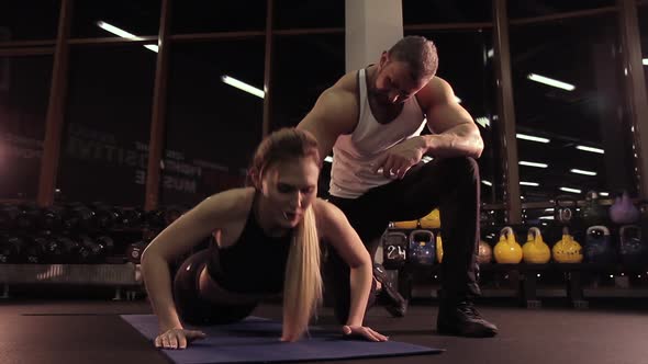 Female Athlete Doing Press-up Under Supervision of Coach in Gym