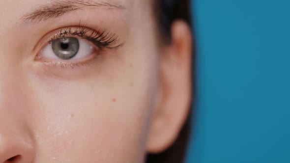 Close-up of Grey Woman Eye Looking To Camera with Wet Skin and Long Brown Eyelashes