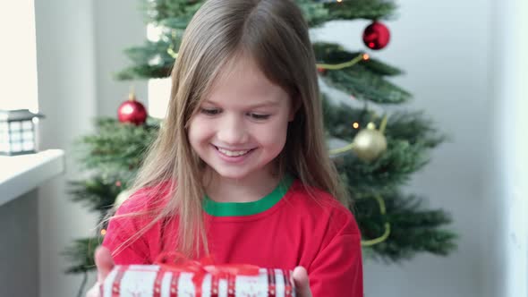 Happy Little Smiling Girl Find Christmas Gift Box From Santa in the Morning