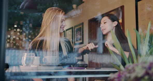 Two Pretty and Happy Girls Relaxing Dancing and Have Conversation in Cafe