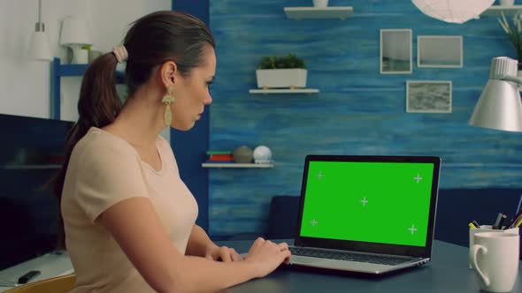 Caucasian Female Typing on Laptop Computer with Mock Up Green Screen Chroma Key Display