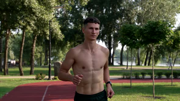 Motivation of Young Muscular Athlete Runs on Running Track in Park Competition