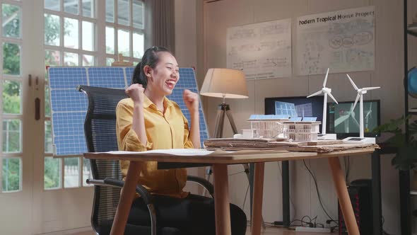 Side View Of Asian Woman Being Happy Succeed Building A Model Of Small House With Solar Panel