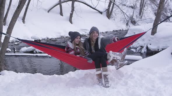 Twin sisters sitting outside in the snow in hammock talking