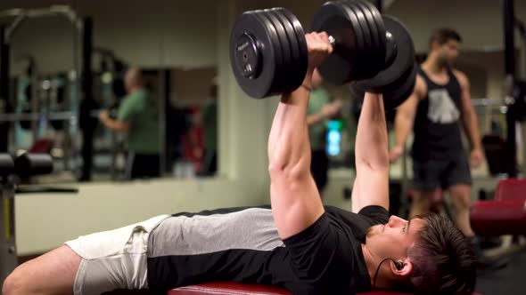 Closeup side shot of bodybuilder doing dumbbell bench presses.