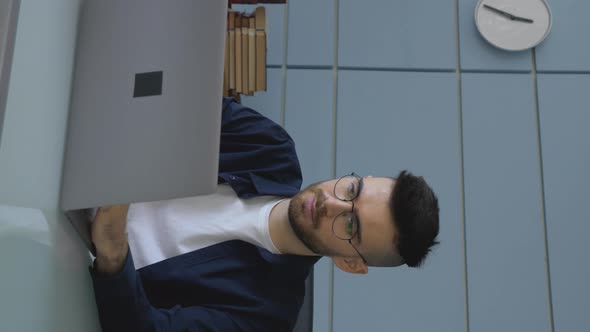 A Young Male Freelancer With Glasses Is Working On An Online Project At A Laptop Computer