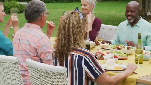 Animation of diverse happy senior female and male friends eating lunch in garden