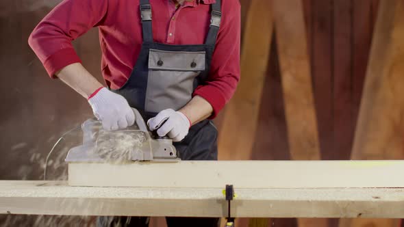 Close-up Hands of Carpenter in Overalls Polish Surface of Blank with Planer