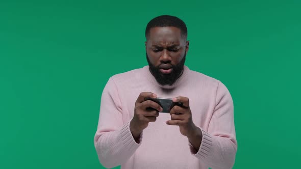 Excited African American Guy Playing Games on Mobile Phone and Wins on Green Screen Chroma Key