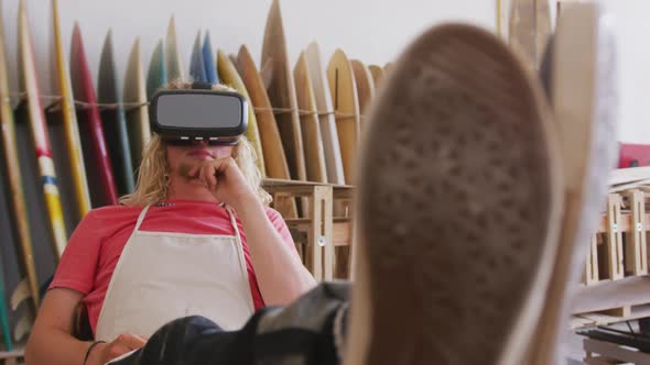 Caucasian male surfboard makers wearing a VR headset
