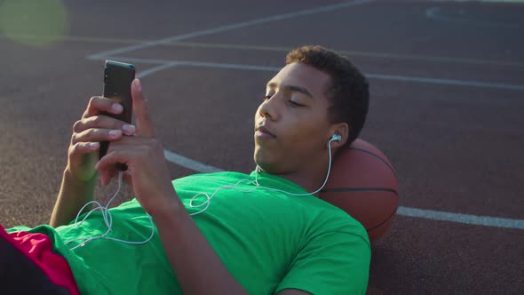 Joyful Basketball Player Listening Music on Phone