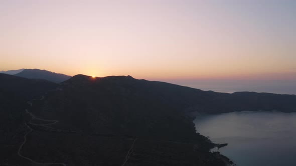 Aerial view of Sunrise above Mountain near Sea. Flying over Coast line in the Morning