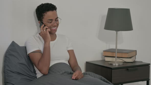 African Woman Talking on Call on Smartphone in Bed