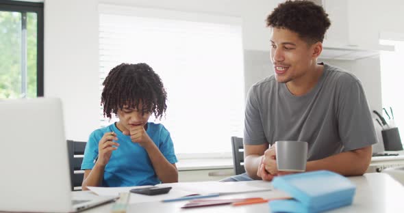 Happy biracial man and his son doing homework together