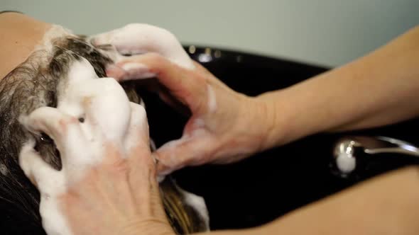 Careful Master Washes Client Hair with Shampoo Above Sink