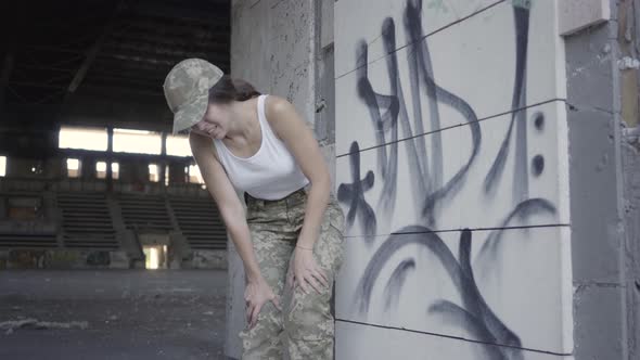 Young Woman in Military Uniform Hiding From Enemy in Dusty Dirty Abandoned Building