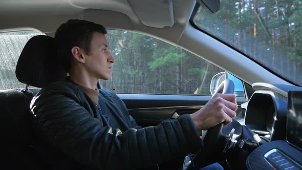 Driver Drives Car Confidently Along Country Road Past Forest