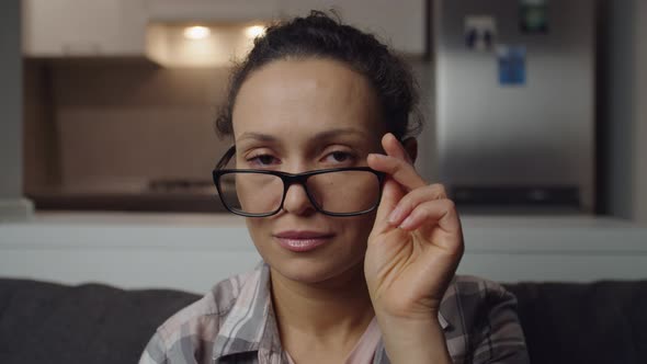 Charming Woman Lowering Her Eyeglasses Having Pensive Look Indoors